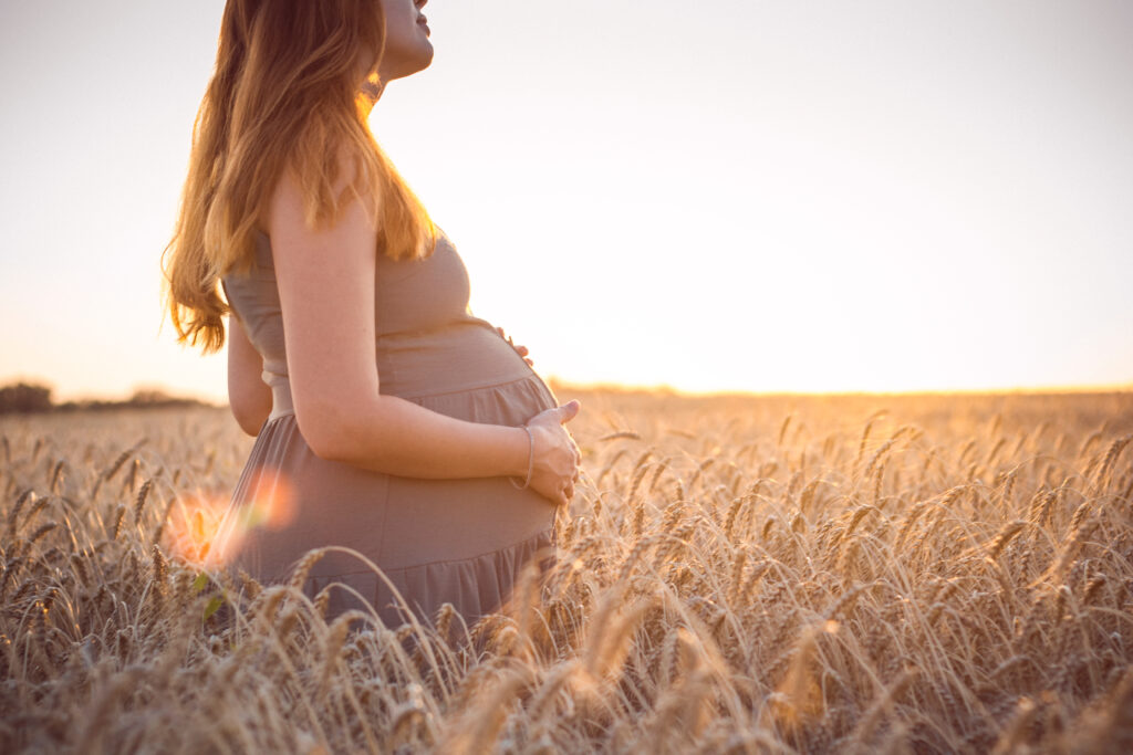Healthy pregnant woman standing in a field