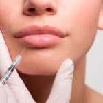 Close up of woman receiving botox injection in lips